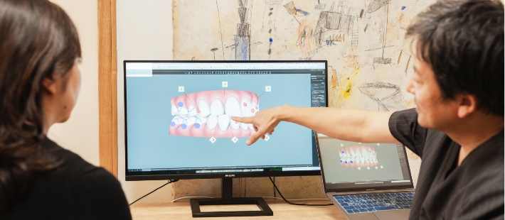 歯科医師と患者がモニターの歯の3Dモデルを見る様子