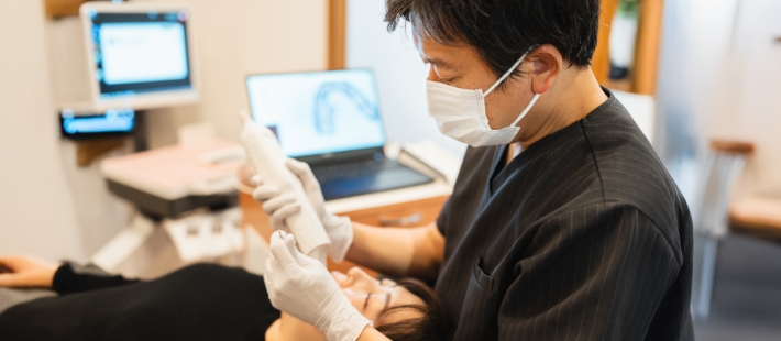 マスクをした関口医師が患者の歯をスキャンする様子