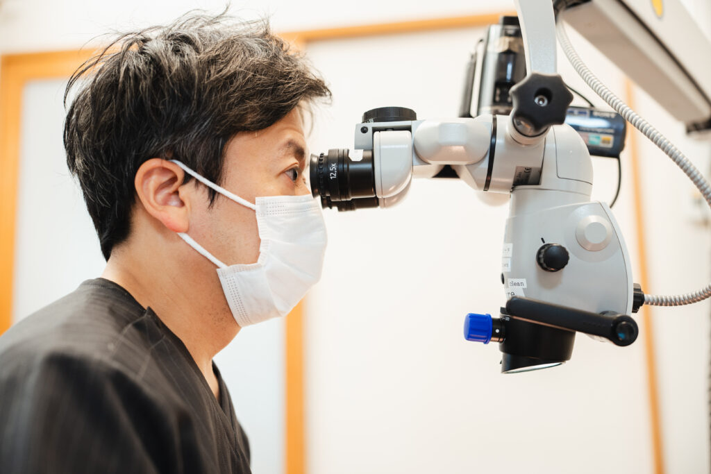 歯科用顕微鏡を覗き込む男性歯科医師