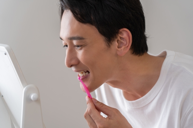 男性が鏡を見ながらフロスで歯のケアをする