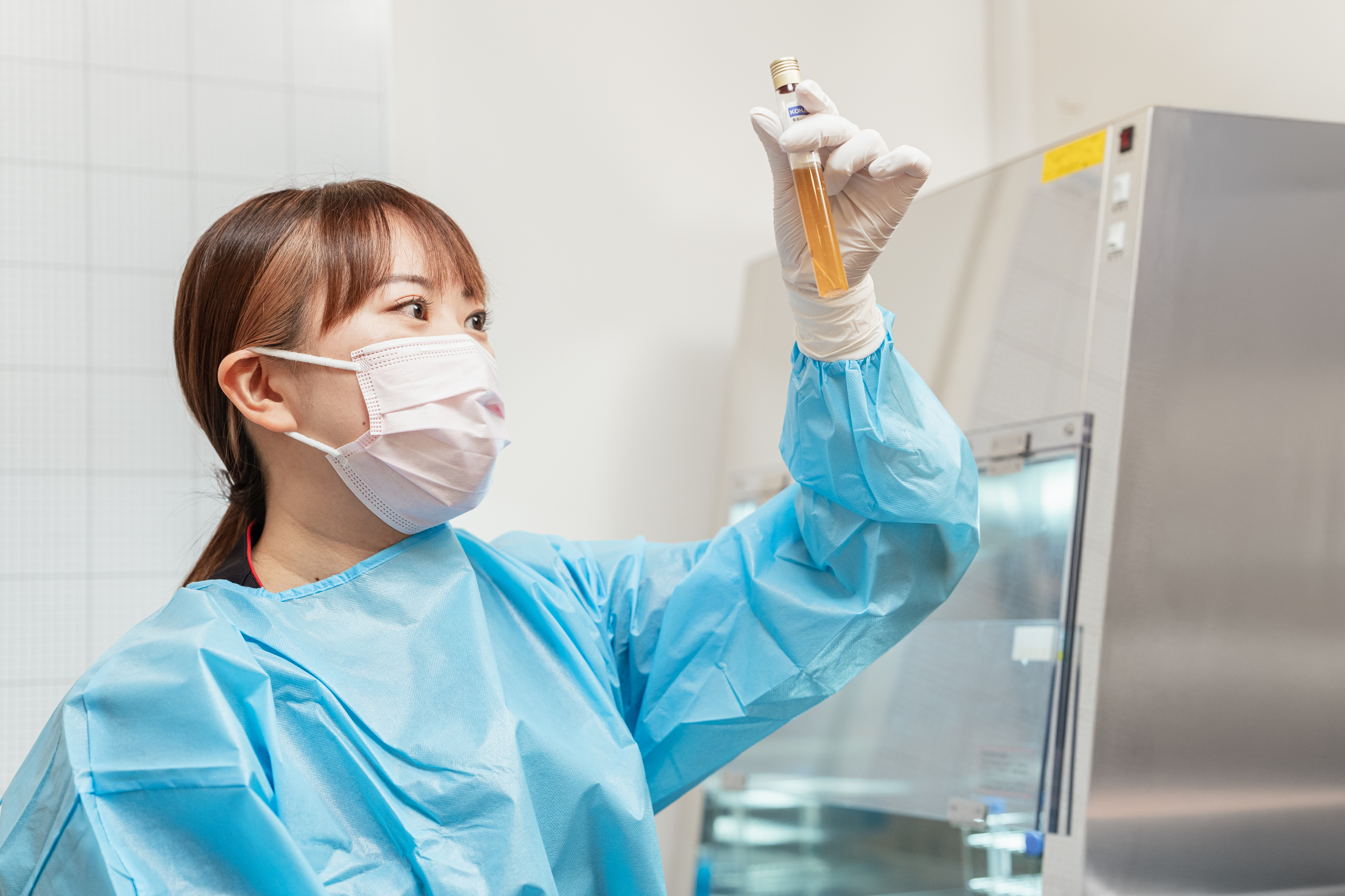 防護服の女性が試験管を観察