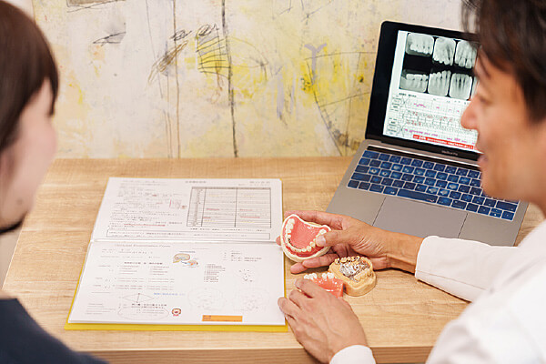 歯科医が患者に歯の模型とレントゲンを見せる