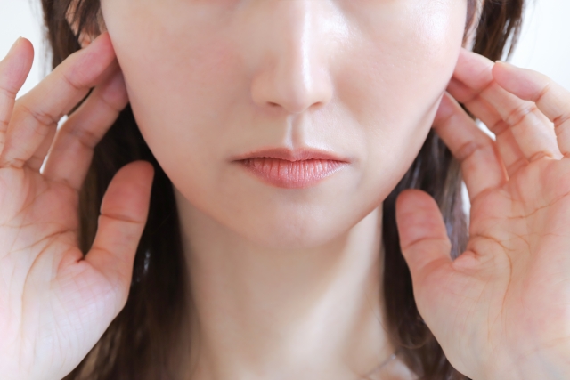 顎関節に手を当てる女性