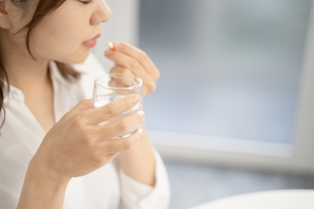 痛み止めを飲む女性