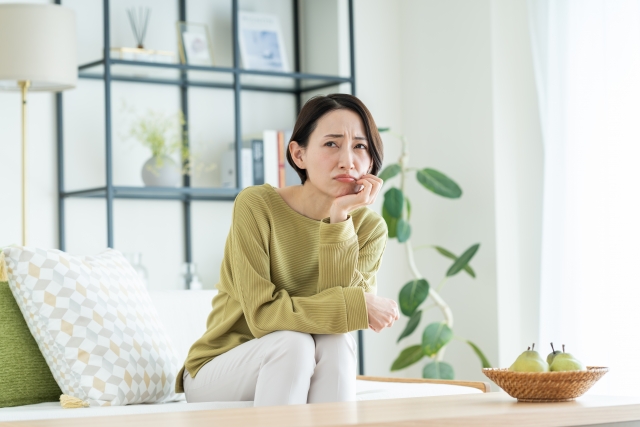 ソファに座って考える女性